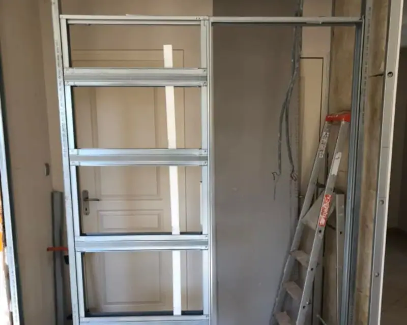 Une ossature métallique posée autour d’une porte, avant les plaques