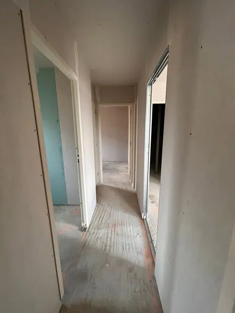 Un couloir entre deux cloisons plaquées, portes ouvertes de chaque côté