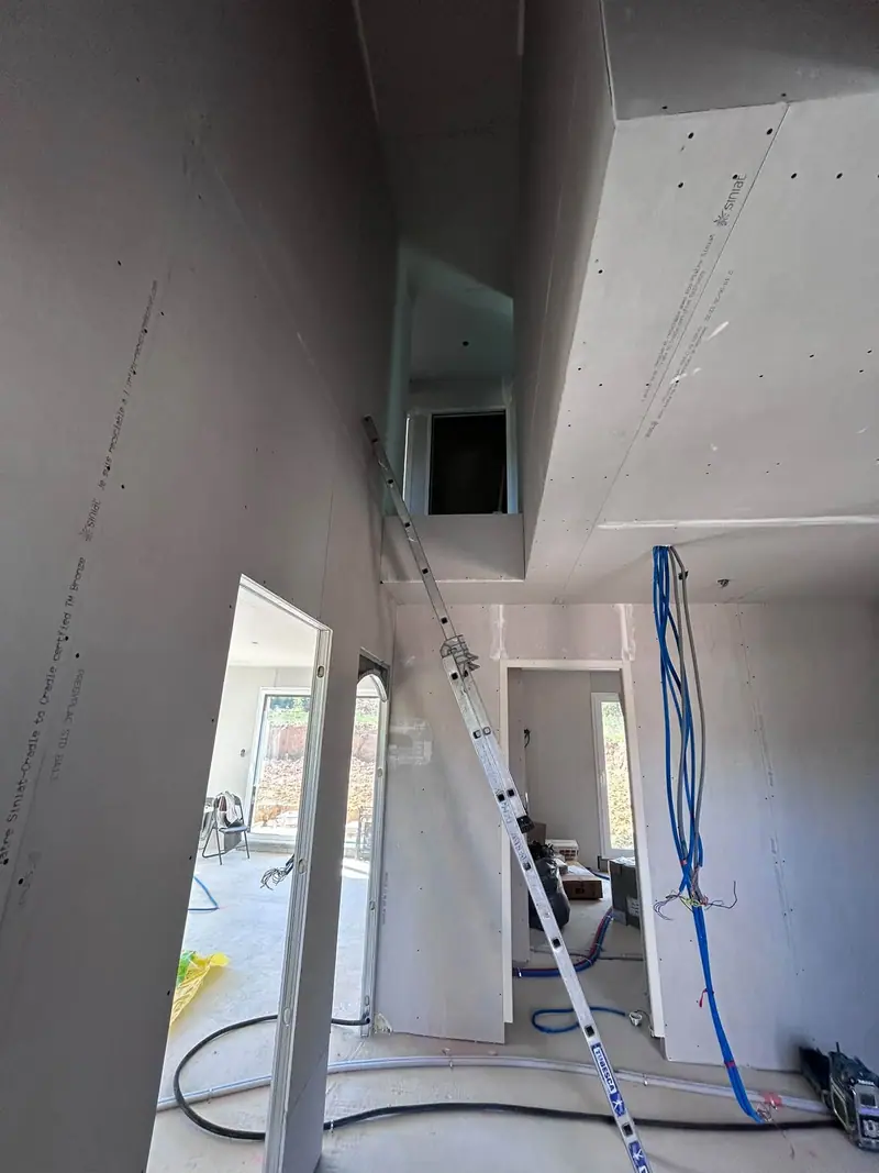 Une mezzanine et un escalier en cours, murs en plaques de plâtre, une échelle