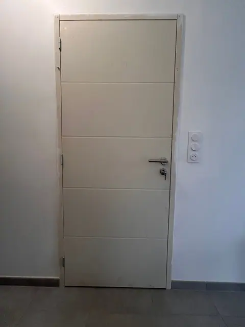 Une porte intérieure blanche à rainures posée dans un mur fini