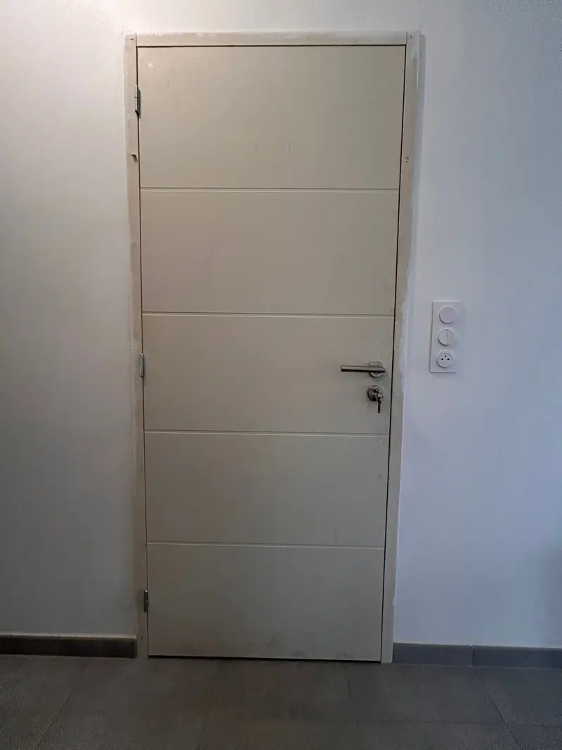 Une porte intérieure blanche à rainures posée dans un mur fini