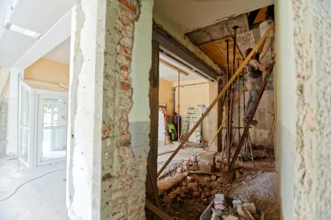 Une rénovation : cloisons démolies, gravats au sol, murs anciens à nu