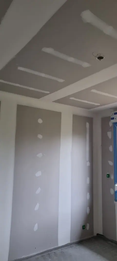 Un plafond et des murs en plaques de plâtre, les bandes et l’enduit posés sur les joints et les vis