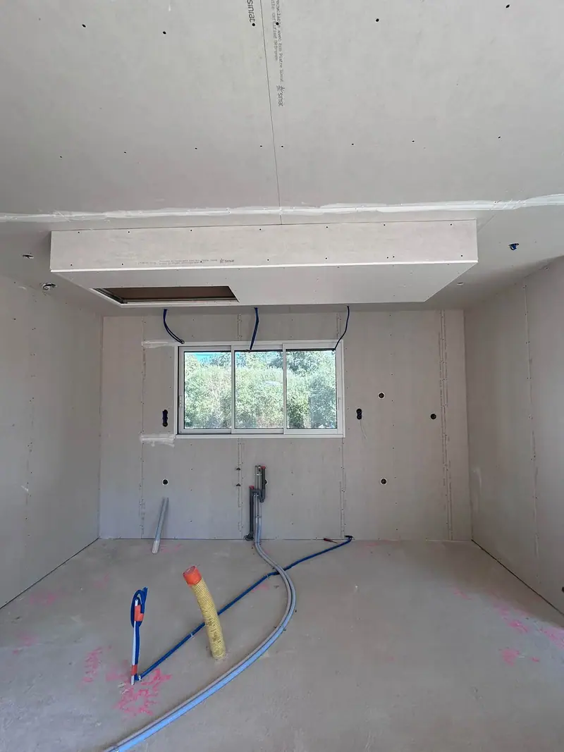 Une pièce plaquée avec un caisson en plaques de plâtre au plafond, au-dessus de la fenêtre
