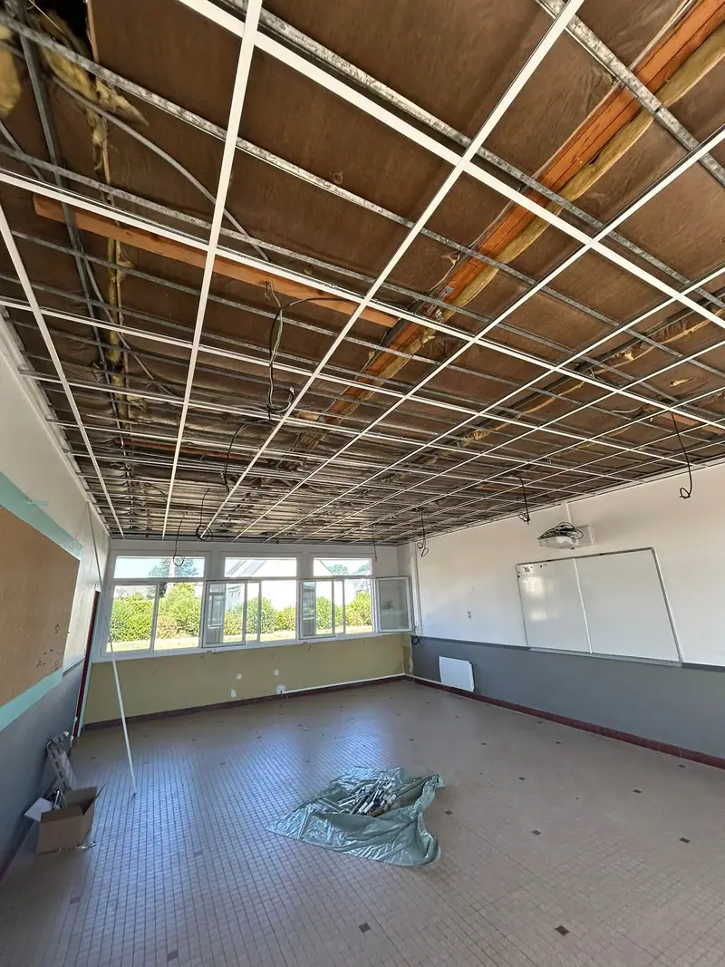 Avant : l’ossature d’un faux plafond à dalles suspendue sous un plafond isolé, dans une grande salle