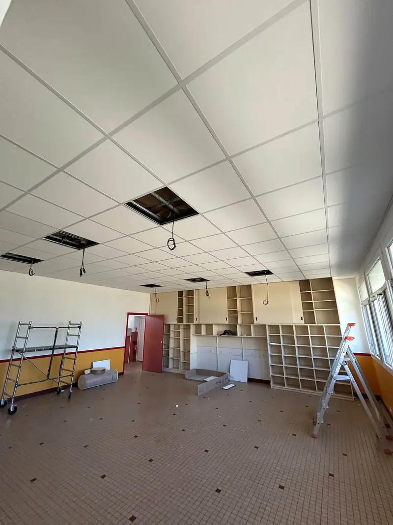 Après : le même faux plafond, les dalles blanches posées, quelques emplacements de luminaires encore ouverts