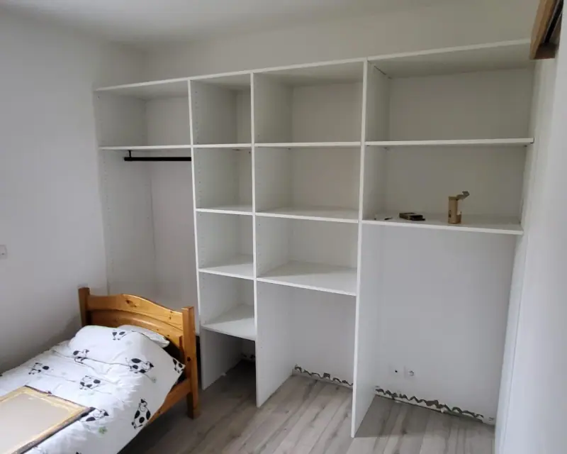 Un placard sur mesure à étagères blanches, dans une chambre