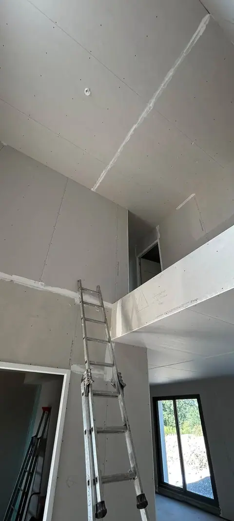 Un volume en double hauteur entièrement plaqué, une échelle appuyée contre la mezzanine