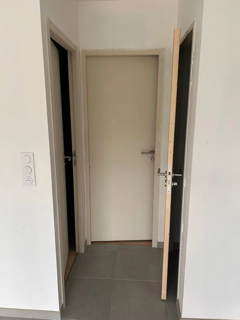 Trois portes intérieures posées dans un couloir aux murs blancs